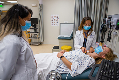 Students performing a mock examination of a patient in the Physician Assistant lab