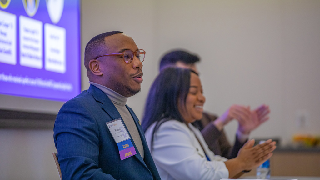 action shot of Marquis Cooper '14 in forefront with Pauline Saintil '17 next to him laughing in reaction to a statement on the DEIB alumni panel