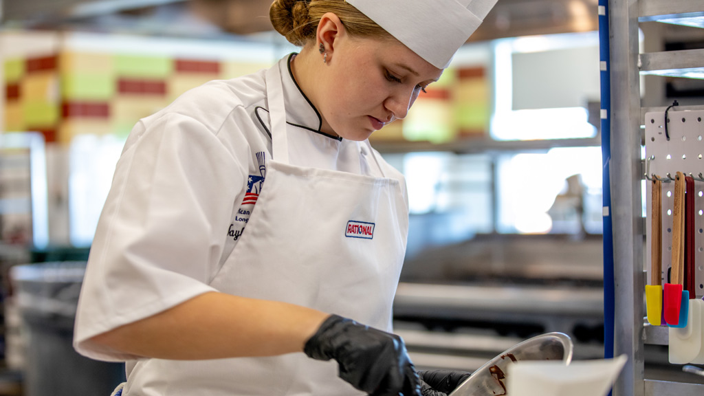 photo of Future Food Competition finalist Taylor DiBiase concentrating as she creates her dessert