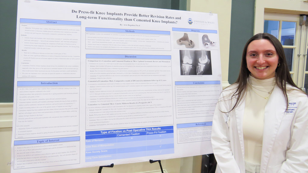 PA student Aris Degaitas poses smiling with her master's research project poster