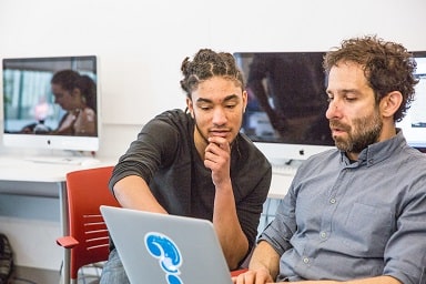 Student and professor discuss work on laptop