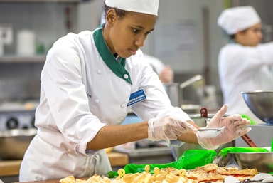 JWU student sifting ingredients for a cake.