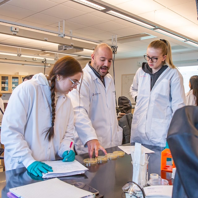 Biology faculty member Christos Dimos working with students in the lab.