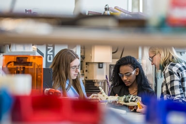 Trio of JWU students working on a robotic arm prototype.