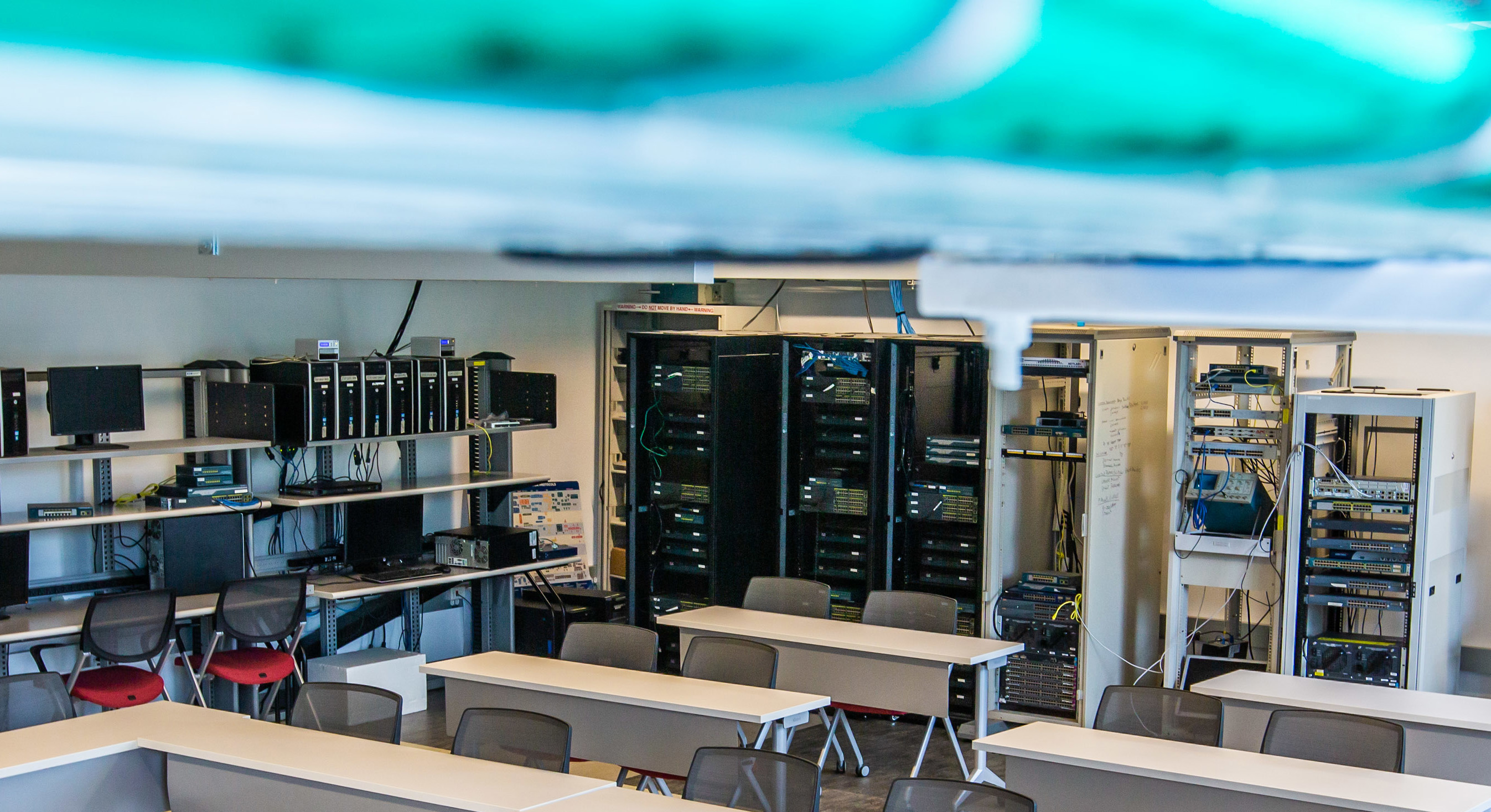 Cybersecurity classroom with server racks and two-seater desks