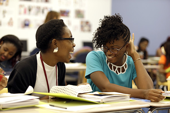 female students sitting in a classroom laughing and smiling