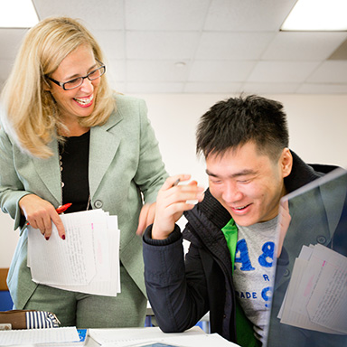 Student and professor laughing together in the classroom
