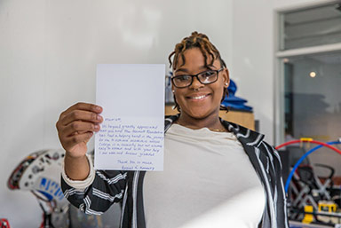 A student holding up the thank you letter she wrote to her scholarship donor