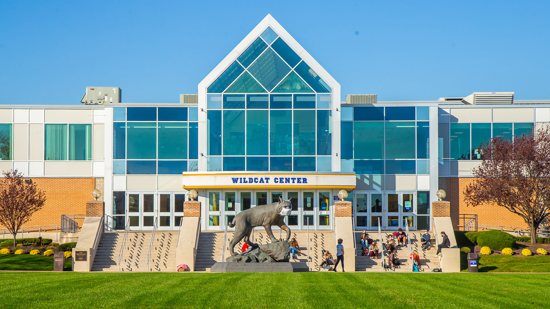 Outside Gaebe Commons during the Fall. Billboard in the midground reads "Here for YOU"