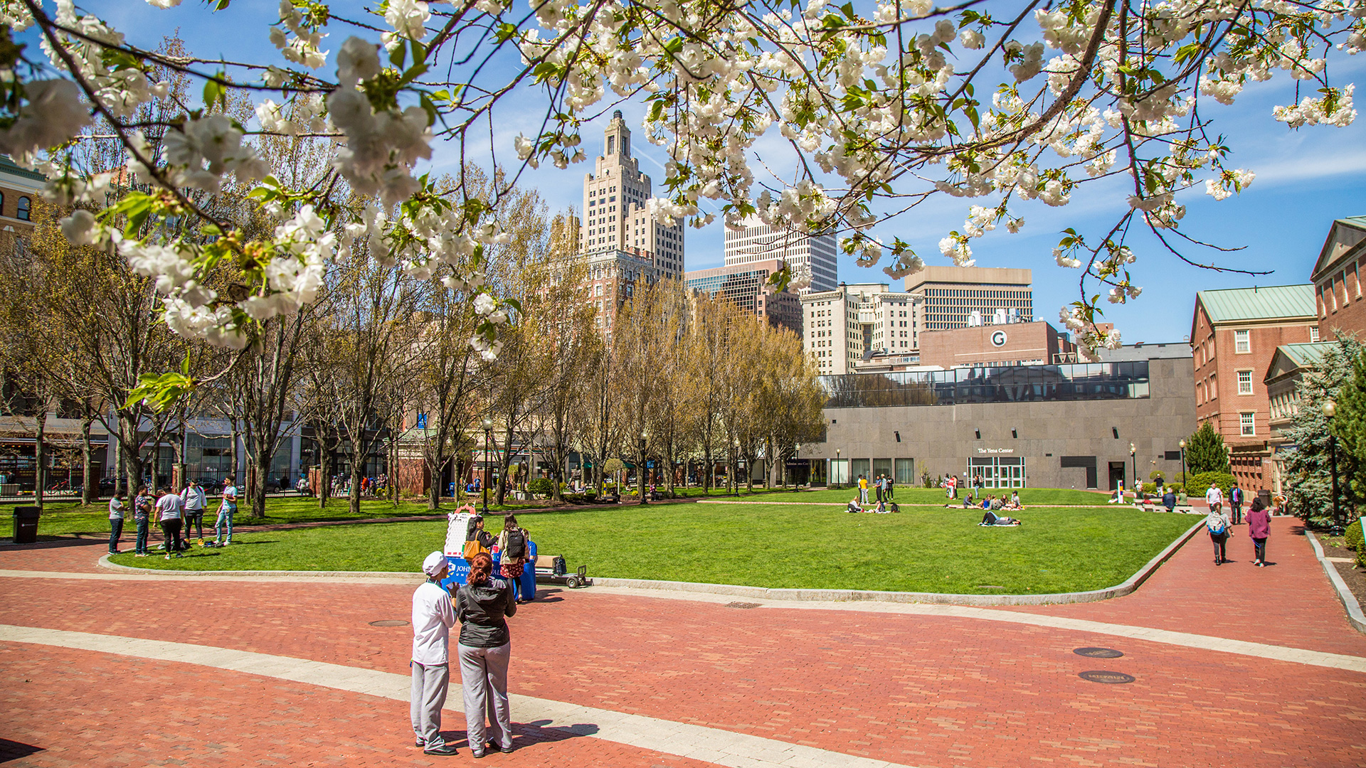 Gaebe commons during spring. students are walk around campus on a bright sunny day with the flowers blooming.