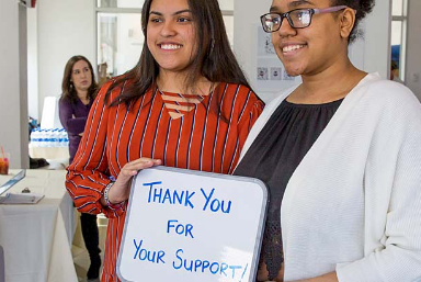 Scholarships and grants - Two female students hold a sign that reads "Thank you for your support!"