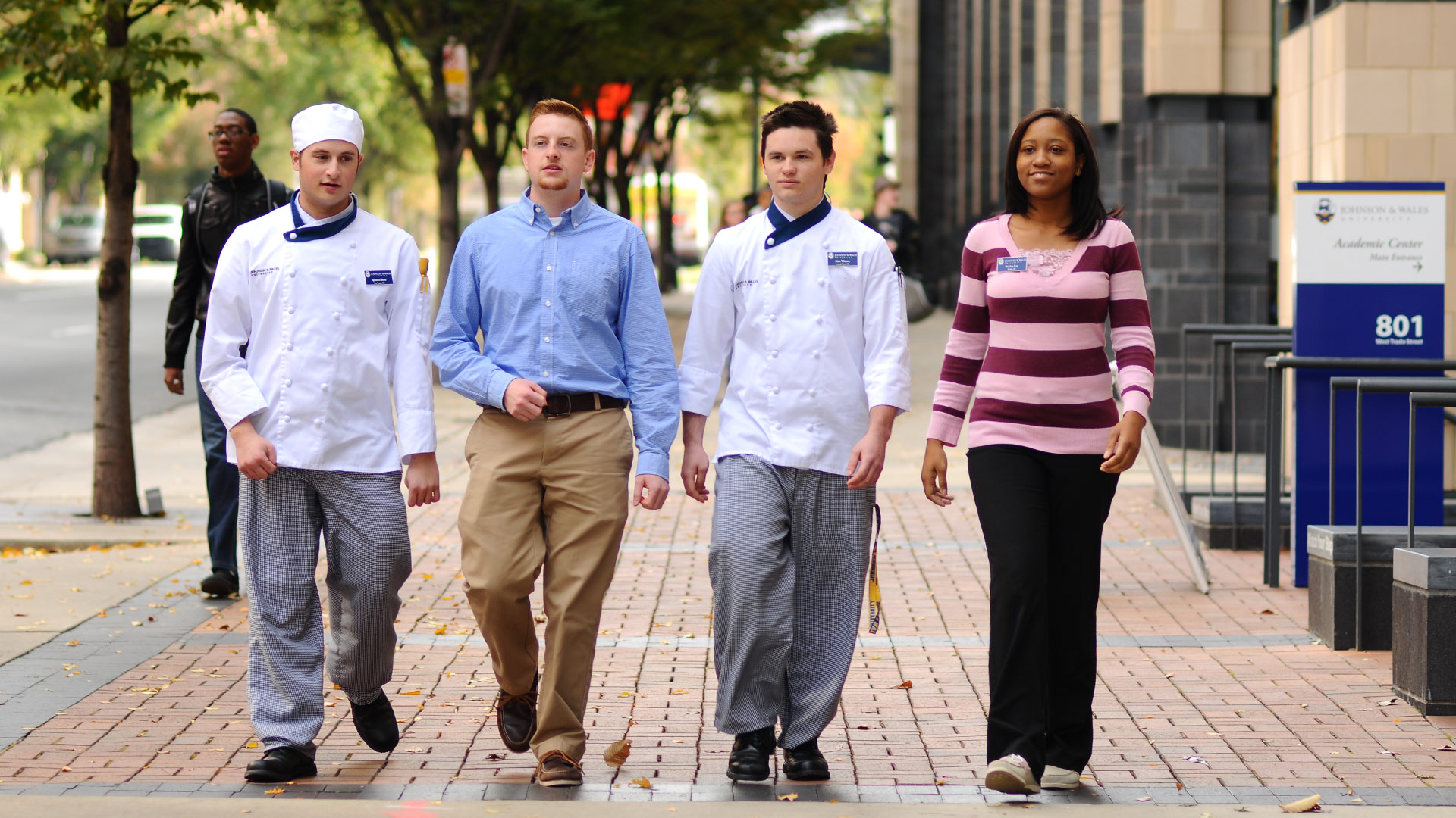 Students walk past the campus entrance on West Trade Street.