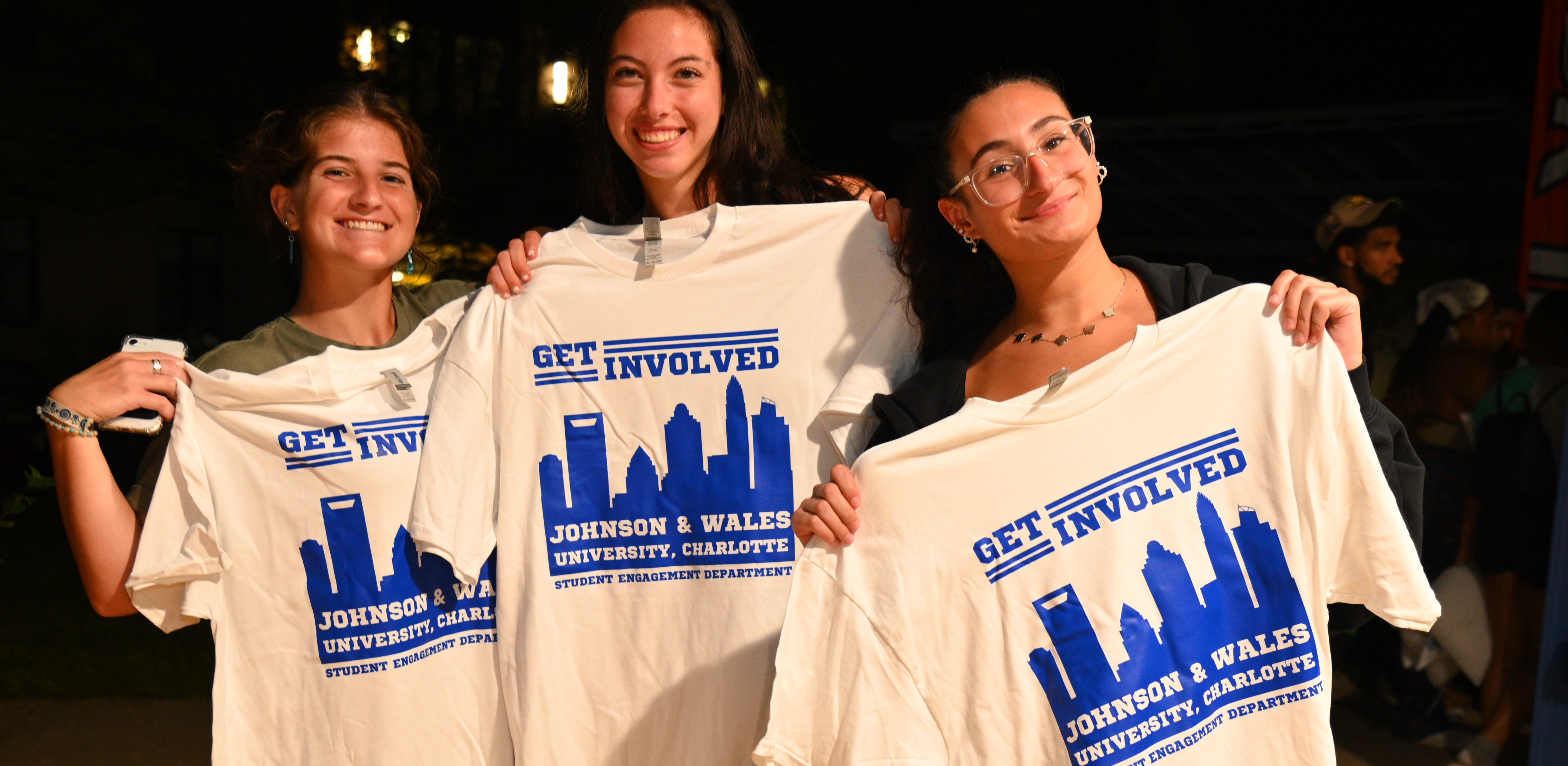 students holding t-shirts with the text "Get Involved"