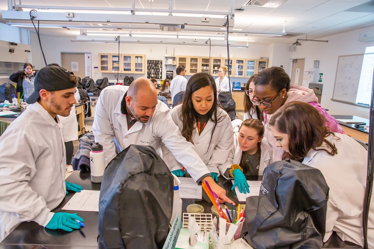 Group of students in science lab gathered around experiment