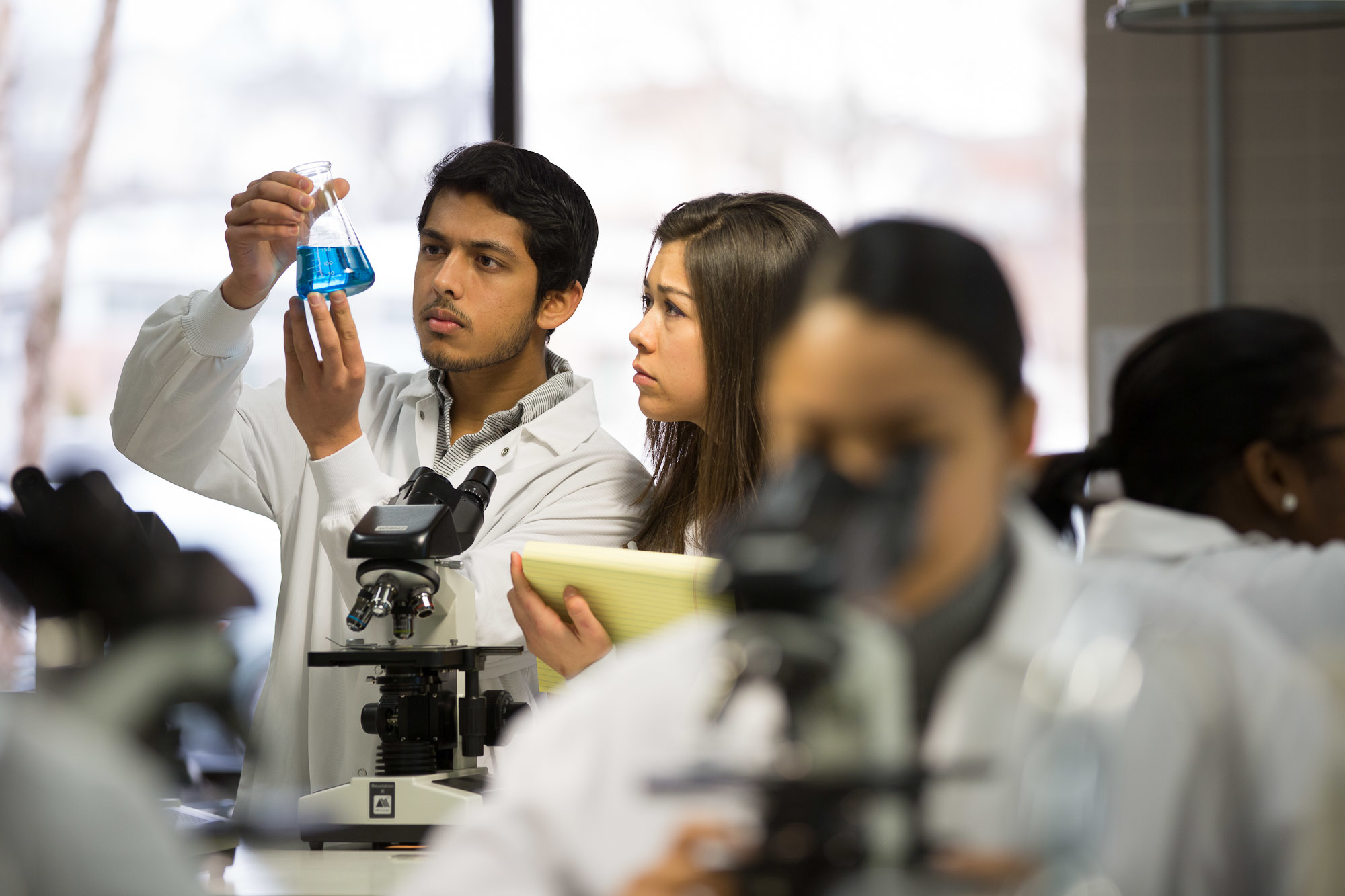 Students in biology lab looking at flask