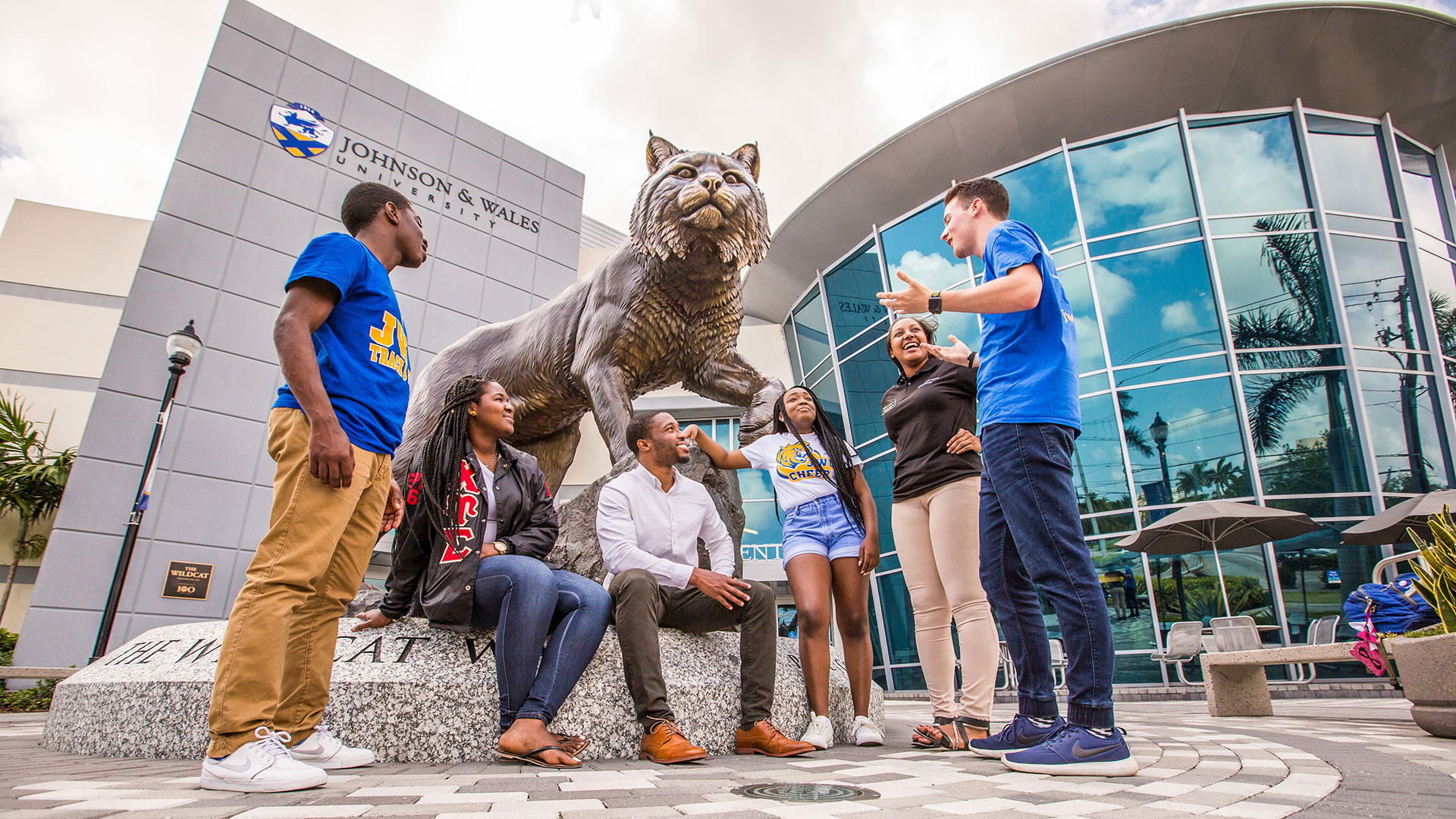 Smiling students sitting by Wildcat statue 