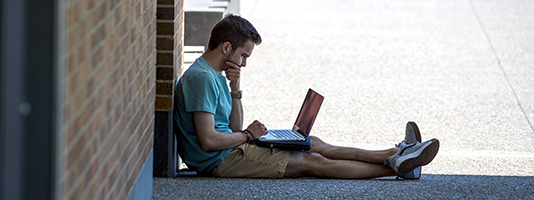 Student working on laptop outside