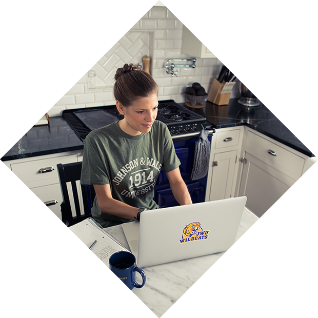Woman with laptop wearing JWU shirt