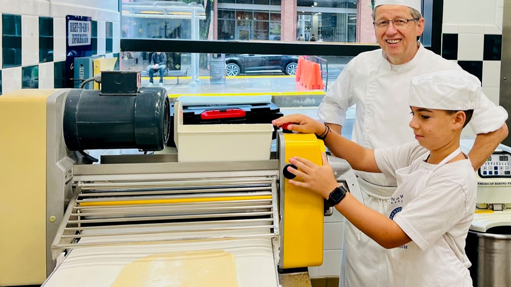 Senior Instructor Harry Peemöeller shows a summer camp attendee how to use a pasta extruder. 