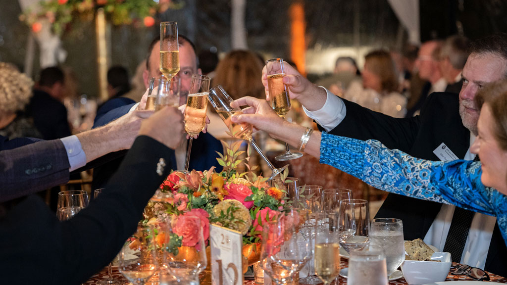 Wine dinner guests share a champagne toast in a formal dinner setting. 