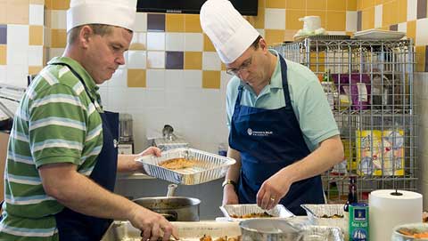 Two men in aprons assemble dishes during a Chef’s Choice class.