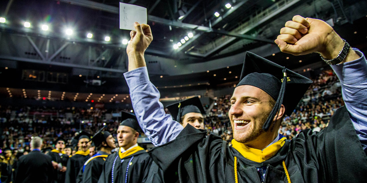 A new JWU Providence grad cheers at Commencement.