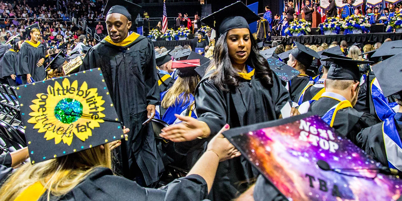 Students showing off the tops of their decorated commencement caps.