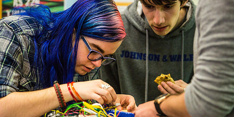 Students tinker with a robot.