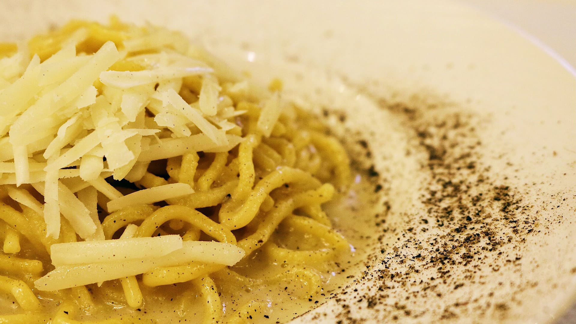 A close up of spaghetti with shredded cheese on top