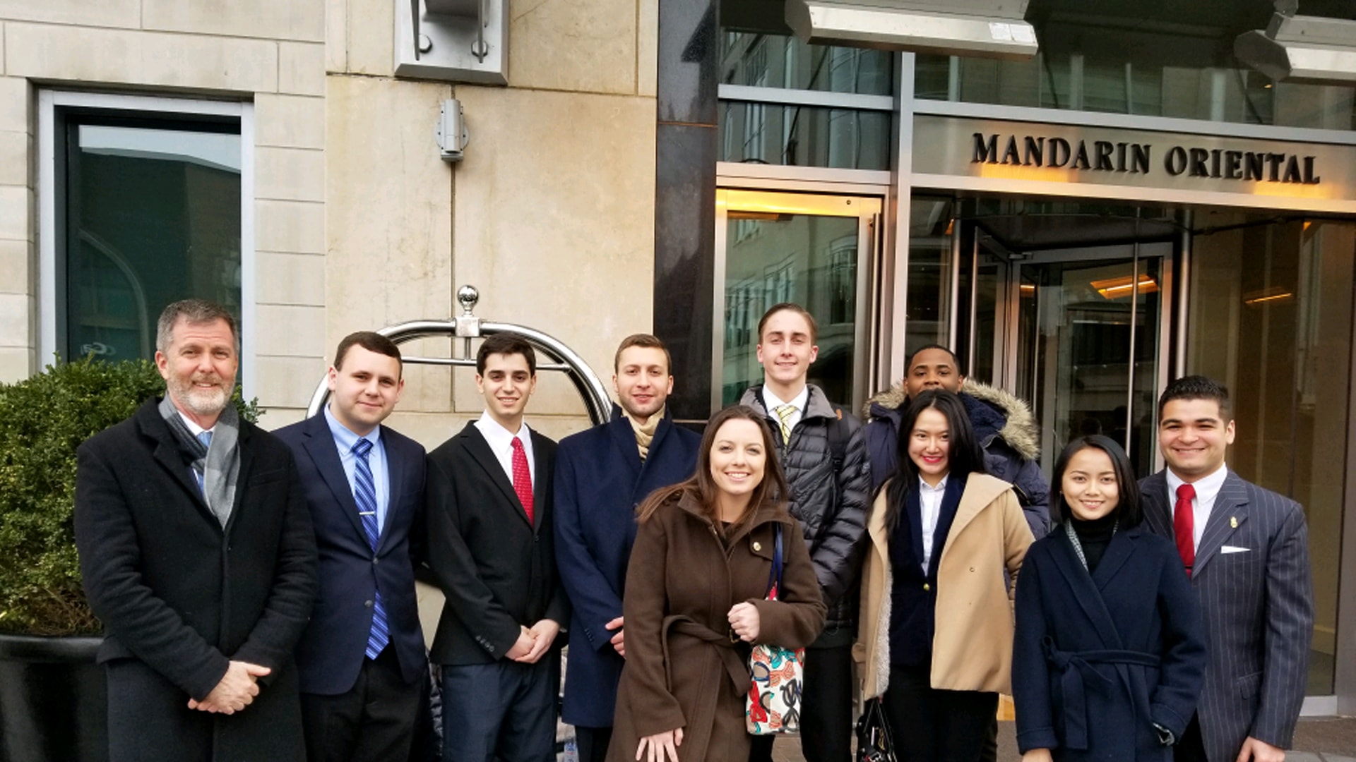 Smiling JWU students lined up in front of the Mandarin Oriental hotel for a group shot