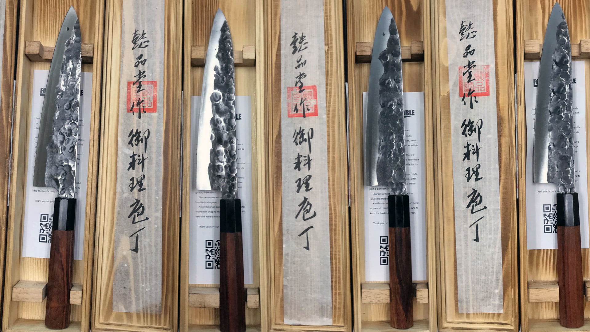 A row of Forge to Table knives in their custom wooden boxes.