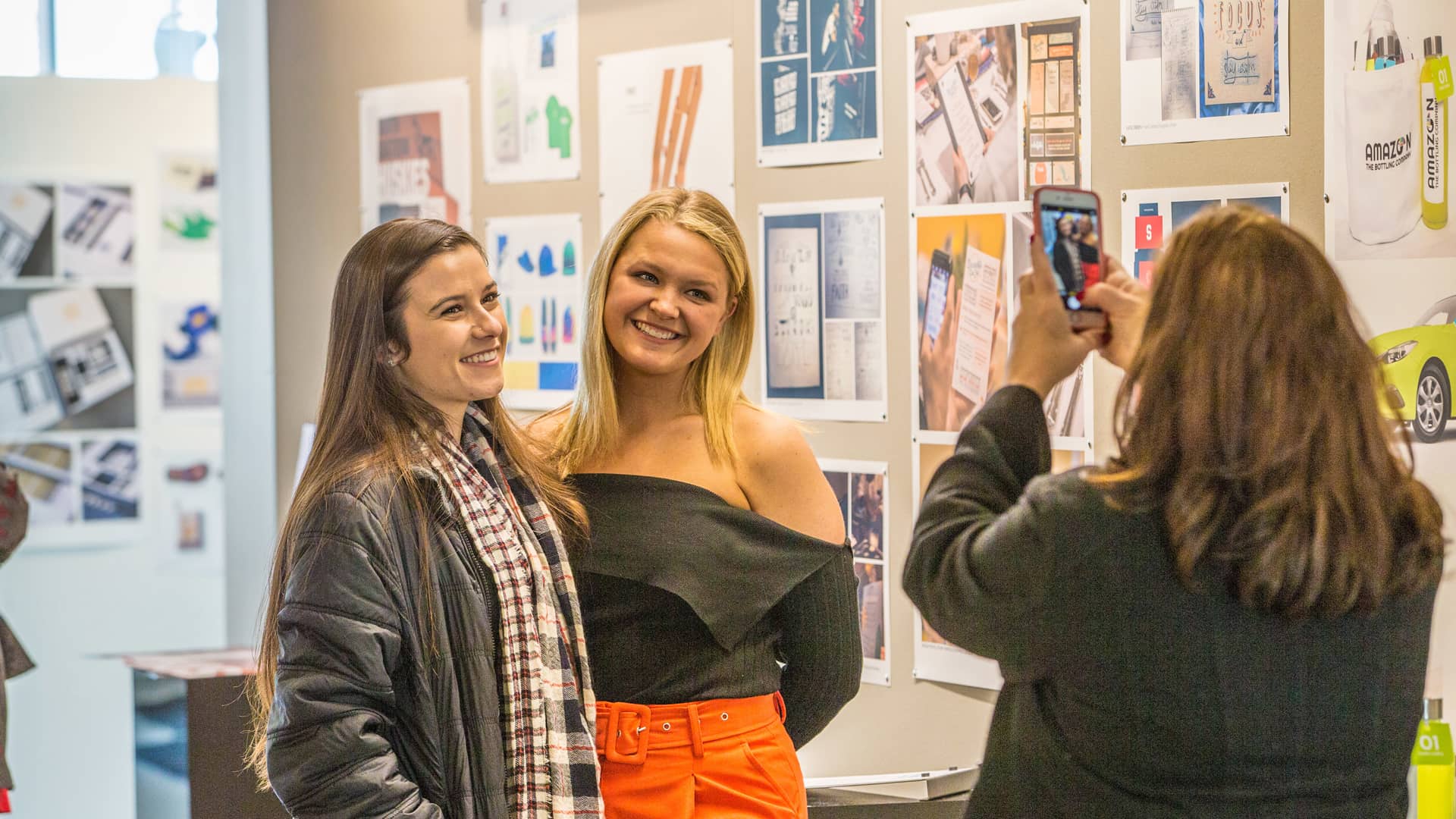 Students pose for photo in front of display of projects