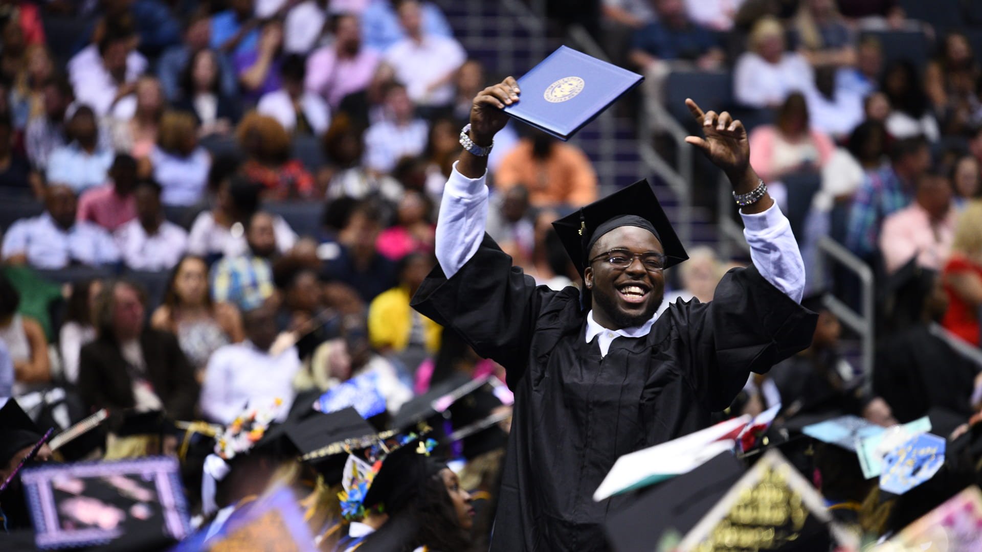 JWU Charlotte graduate holding diploma with joy