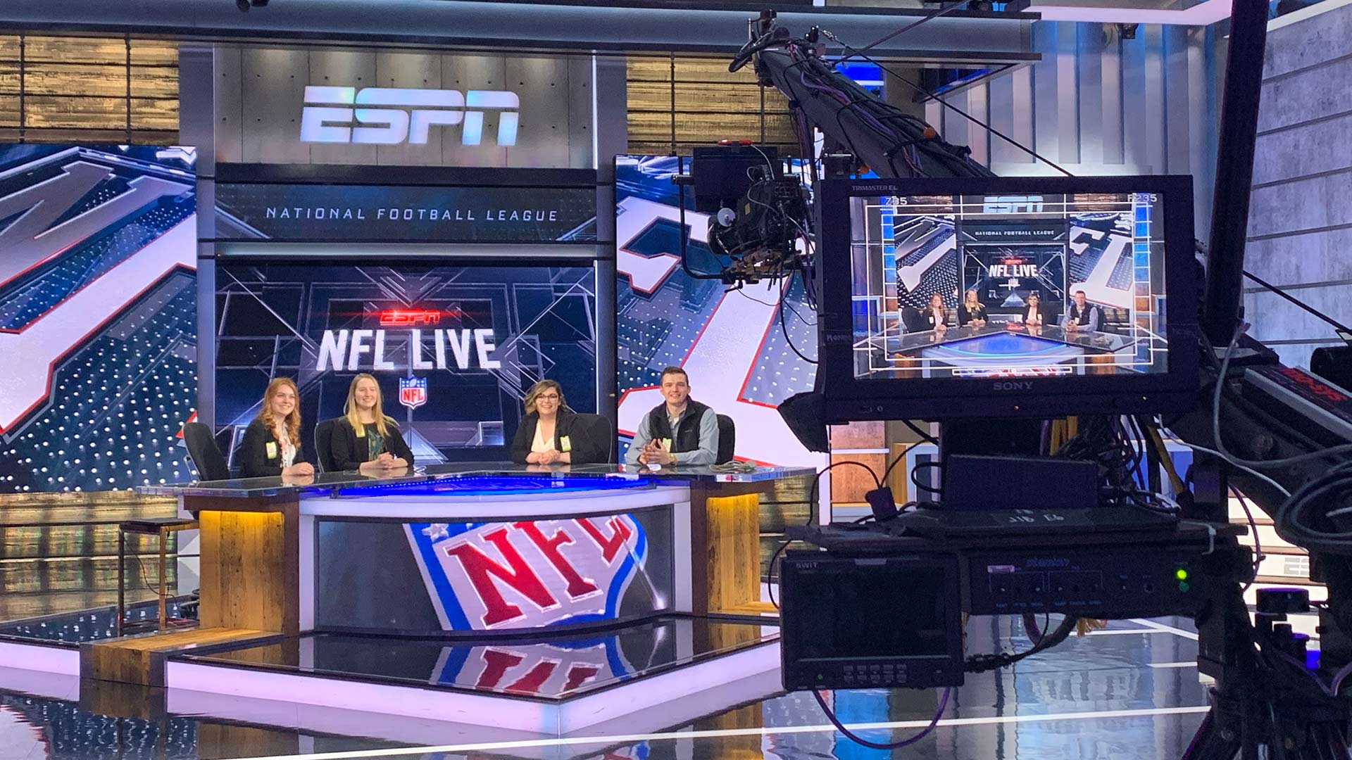 Students test out the NFL table while a camera looks on.