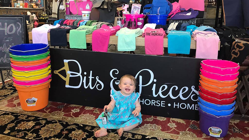 Tierney Boyd's daughter sitting in front of a clothing display in the Bits & Pieces shop