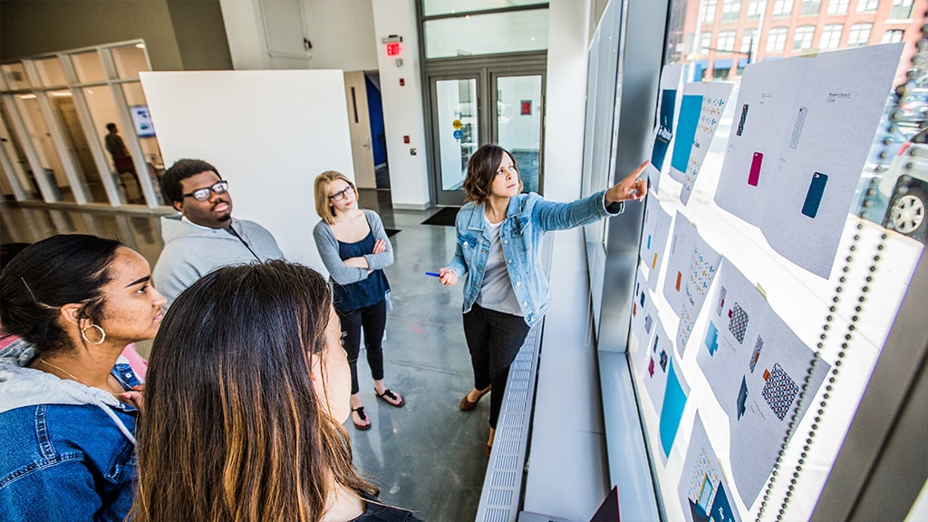 Students with a professor looking at a project