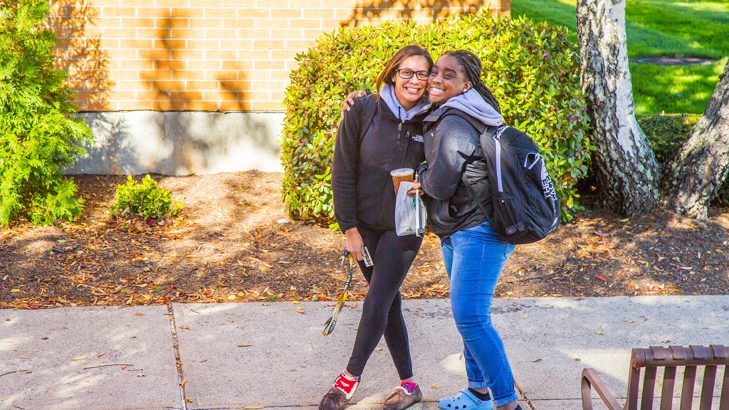 Two students hug on campus in front of dorm