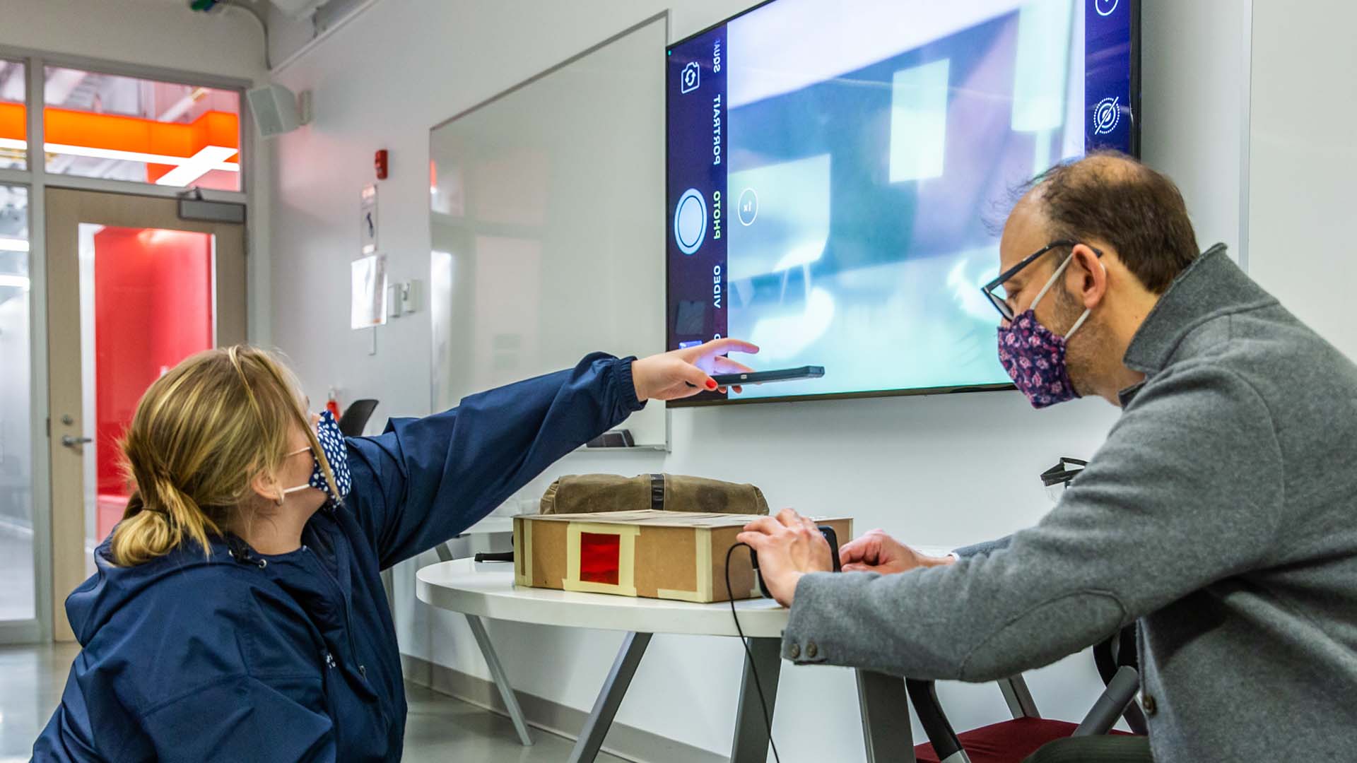 Associate Professor Jonathan Harris helps a student set up her project during a class presentation. 