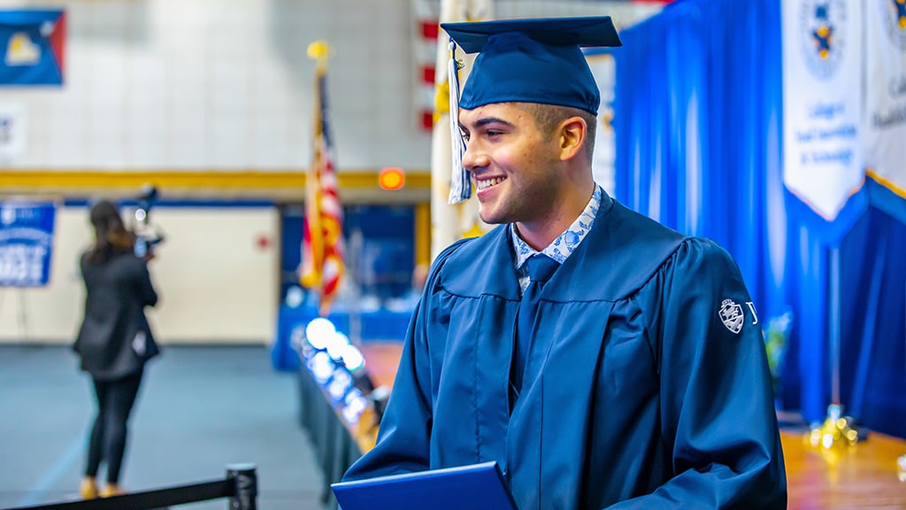 photo of a male JWU student proudly wearing cap and gown