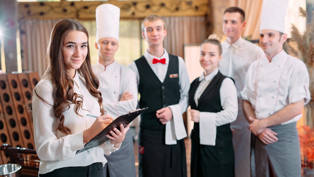 Hotel manager with team holding clipboard