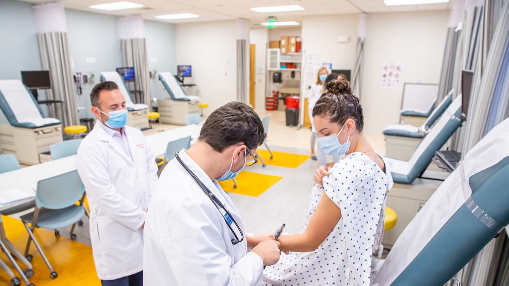 PA student examining a patient in a clinical lab setting.