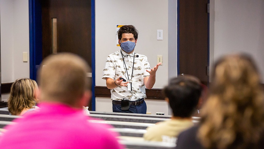 a student ambassador in a classroom setting presents to prospective students and their families