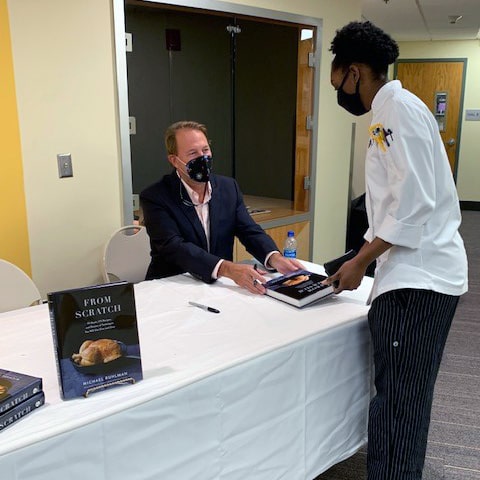 Author Michael Ruhlman chats with a student during a book signing at JWU Providence.