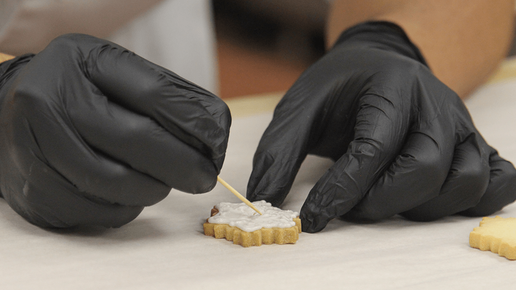 closeup of using a toothpick to spread icing on the cookie