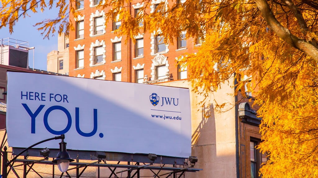 "Here for you" JWU billboard against a cityscape