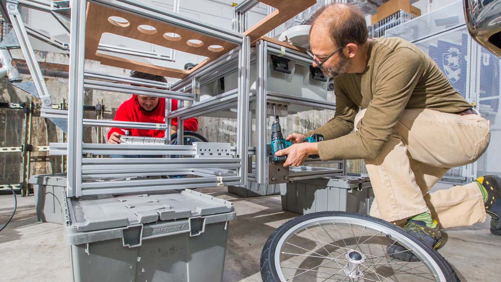 Associate Professor Jonathan Harris works with a student to put the finishing touches on a bike cart prototype.