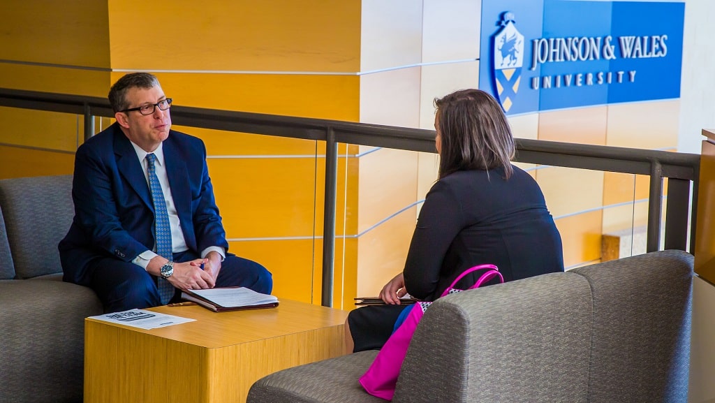 A male mentor advises a female student in a JWU lobby.