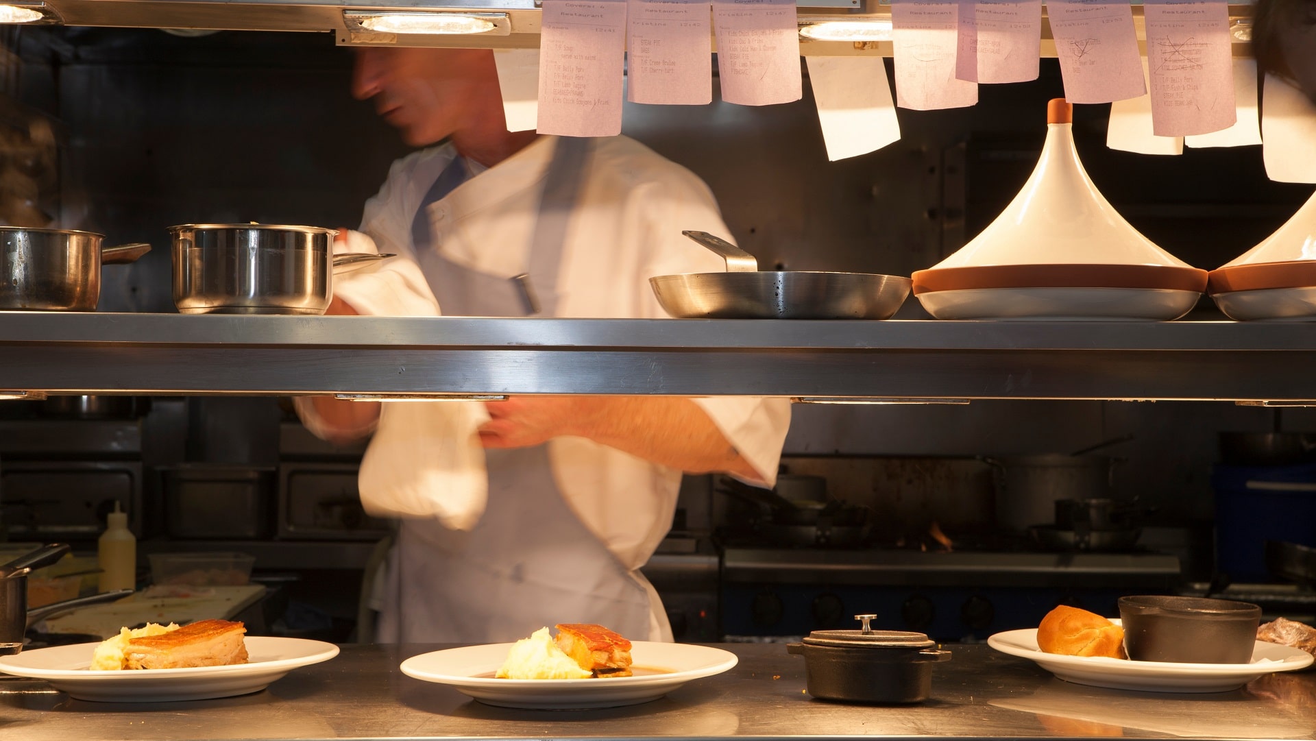 Server stands behind line in restaurant kitchen