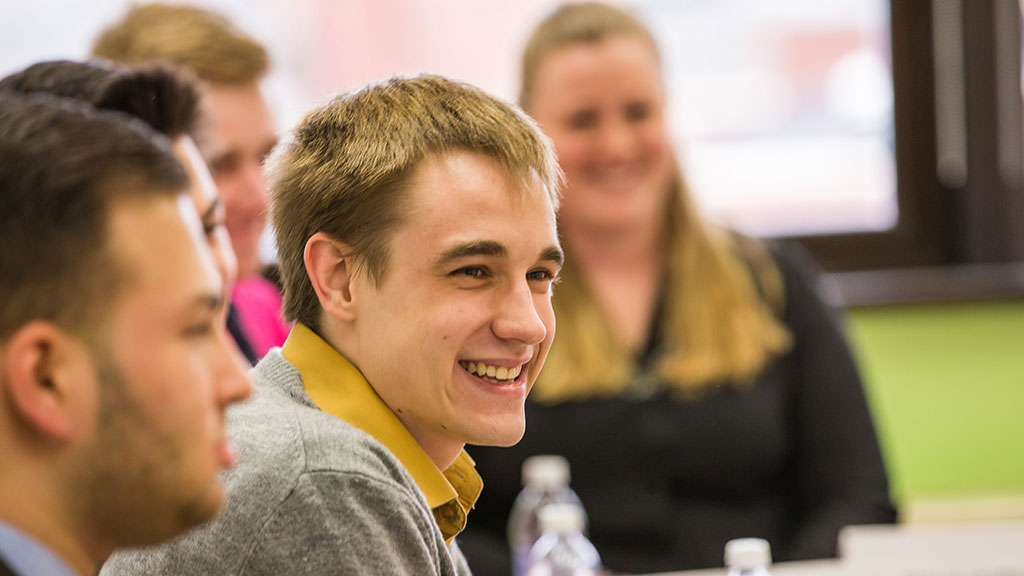 a male student smiles while in a classroom