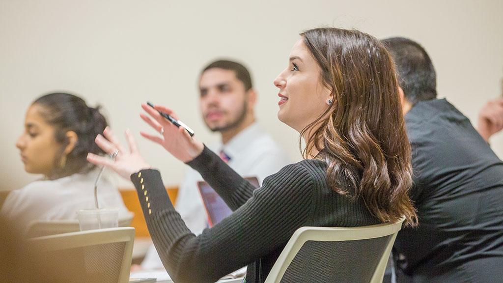 a female student gestures excitedly as she explains a concept in class